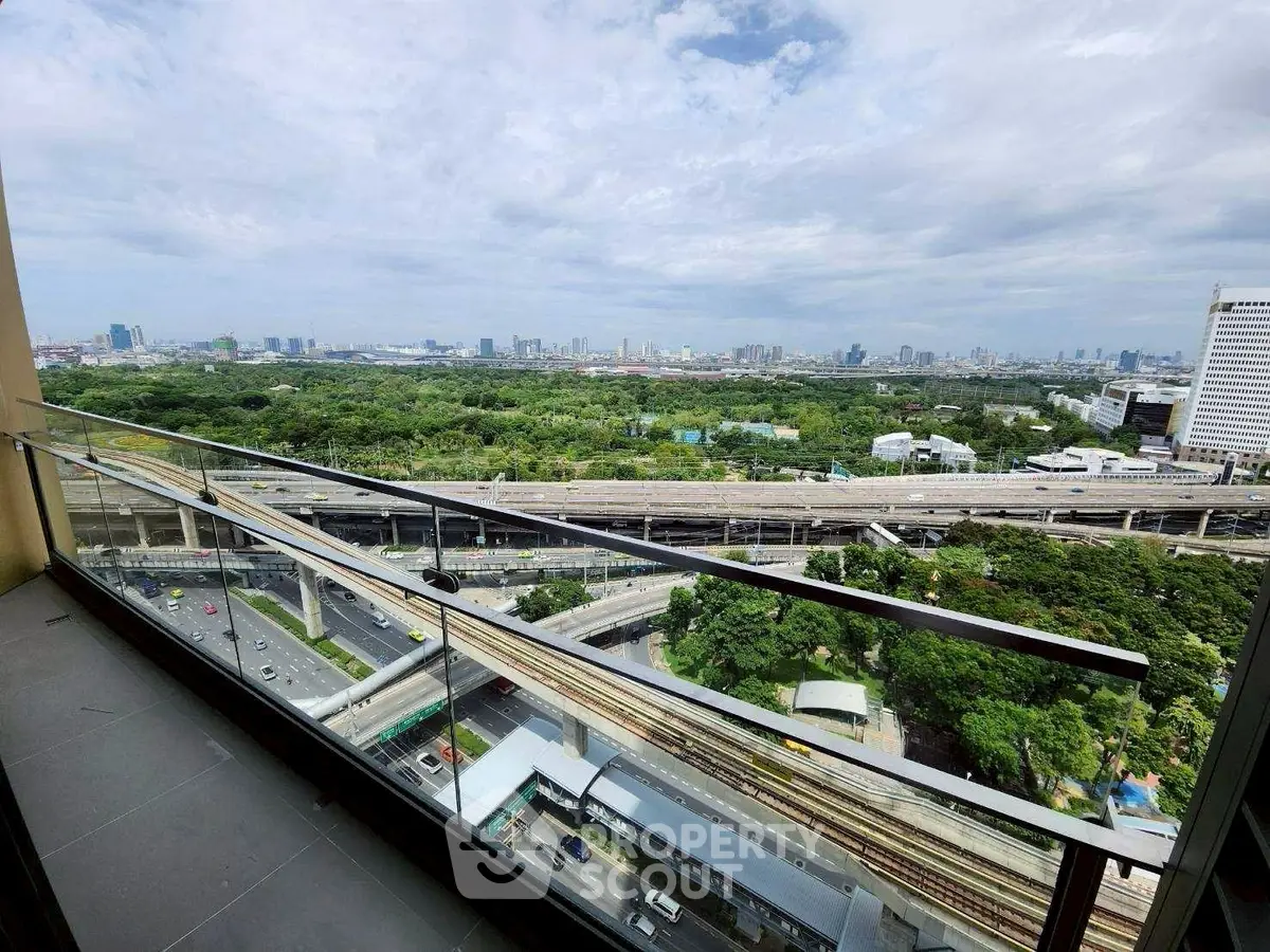 Stunning cityscape view from high-rise balcony overlooking lush greenery and urban skyline.