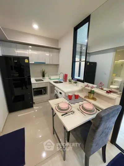 Modern kitchen with sleek appliances and cozy dining area in stylish apartment.