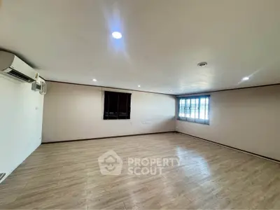 Spacious empty room with wooden flooring and air conditioning, ideal for customization.
