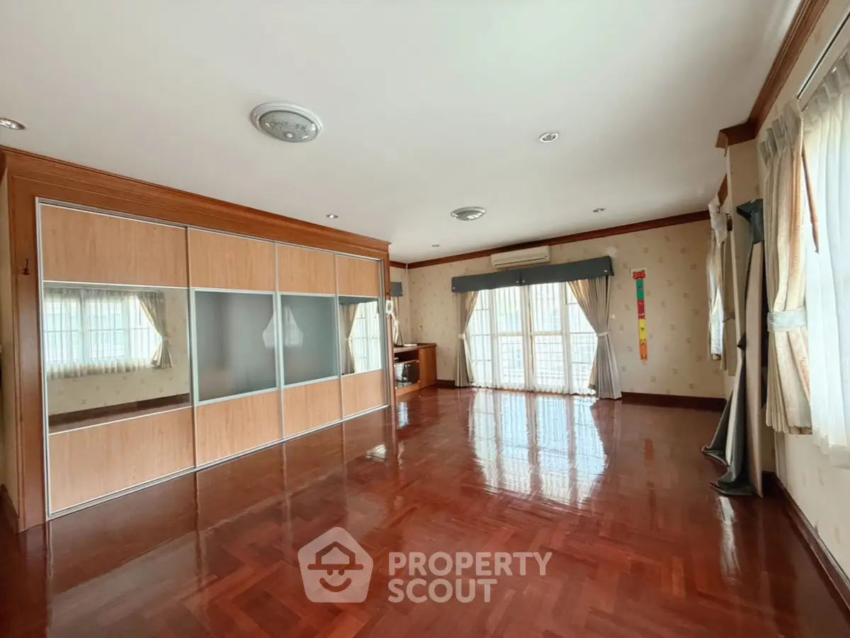 Spacious living room with wooden flooring and large windows for natural light.