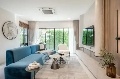Modern living room with blue sofa, large windows, and stylish decor
