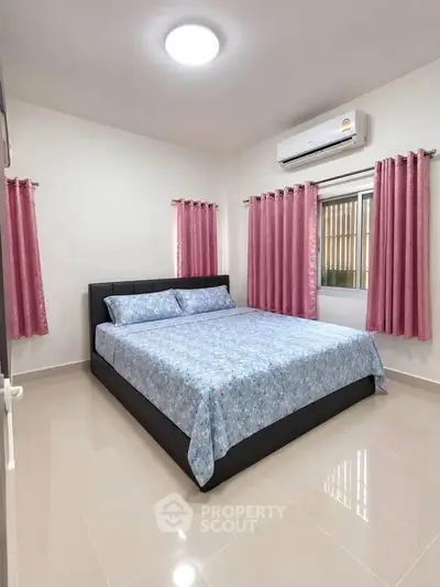 Spacious bedroom with modern decor and natural light, featuring a comfortable bed and air conditioning.