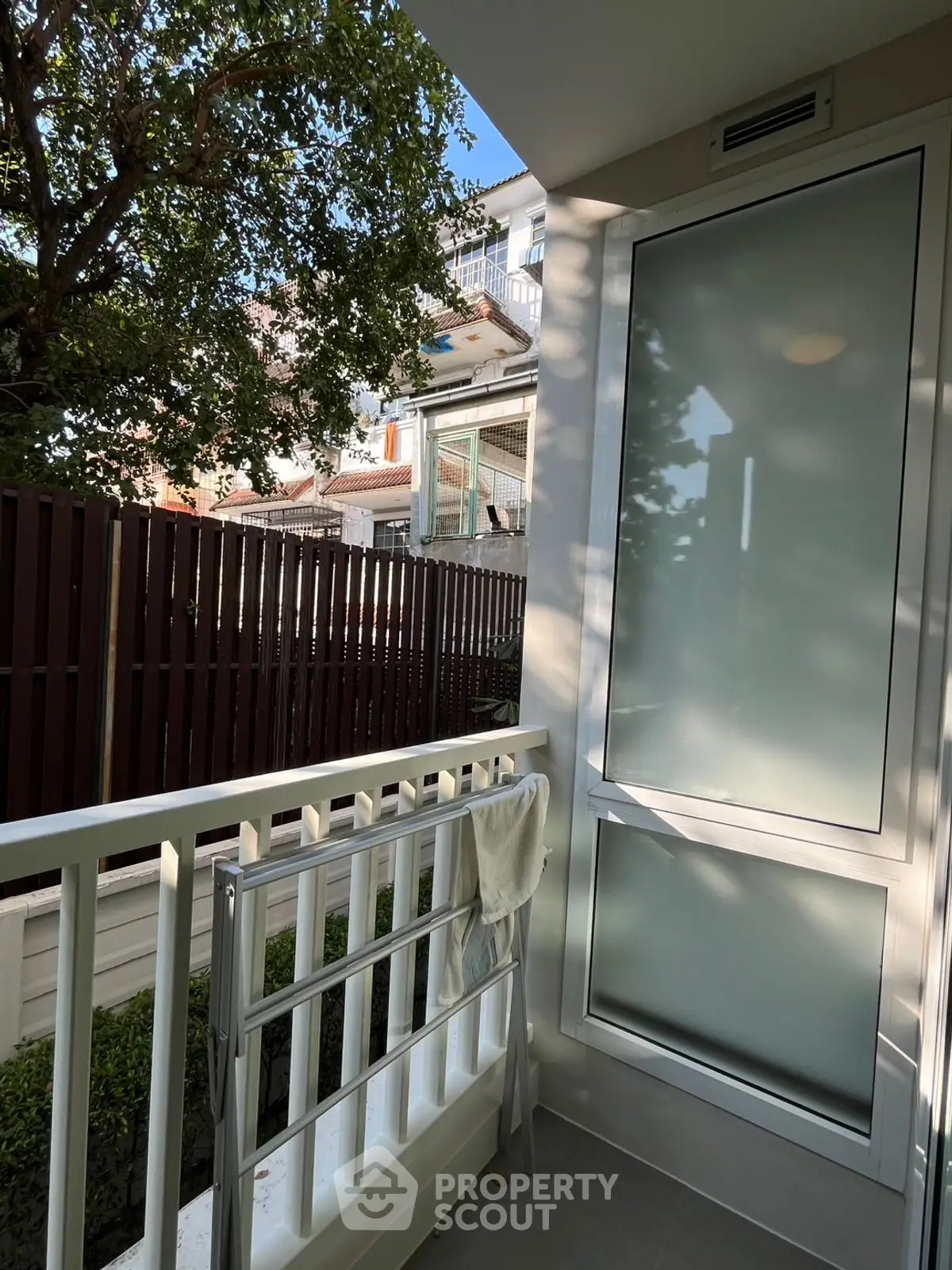 Charming small balcony with privacy screen and lush greenery view, perfect for relaxation.