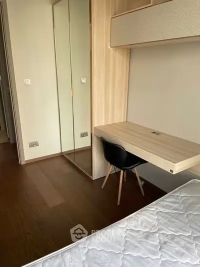 Modern bedroom with built-in desk and mirrored wardrobe, perfect for compact living.