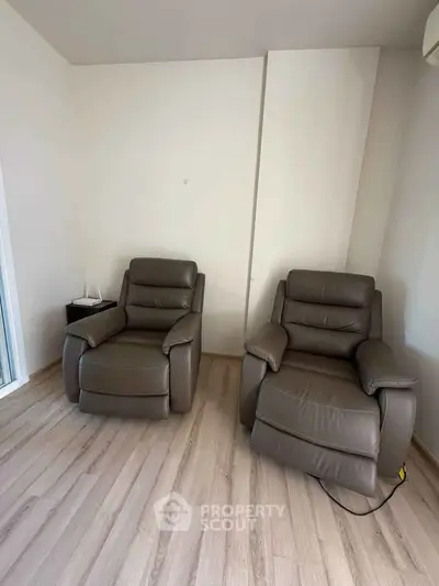 Cozy living room with two brown leather recliners on wooden flooring, perfect for relaxation.
