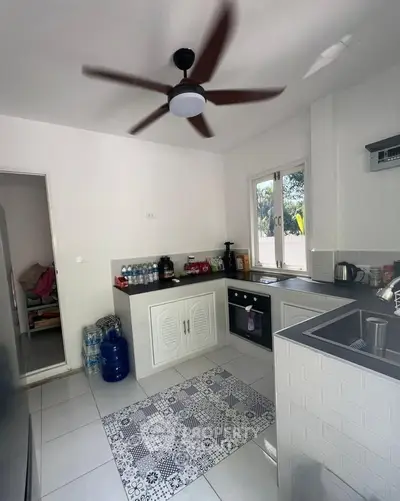 Modern kitchen with sleek design, featuring a ceiling fan, built-in oven, and ample natural light.