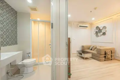 Modern apartment interior with cozy living room and adjacent bathroom, featuring stylish decor and efficient layout.