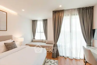 Elegant bedroom with cozy seating area and large windows for natural light