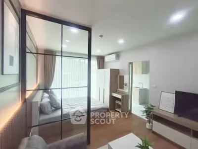 Modern studio apartment with glass partition, cozy bedroom, and stylish living area.