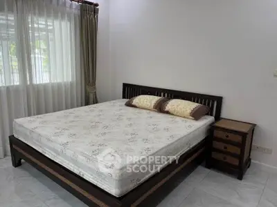 Spacious bedroom with large bed and natural light from window