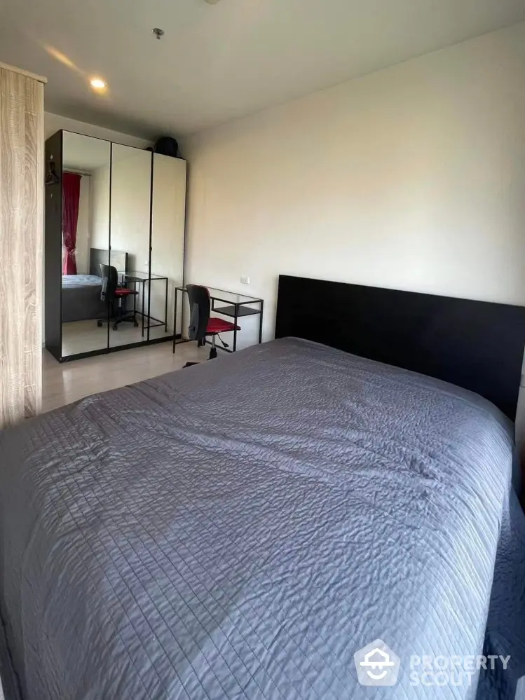 Modern bedroom with stylish mirrored wardrobe and cozy bed setup.