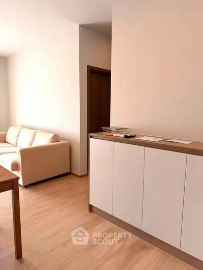 Modern living room with light wood flooring and sleek white furniture