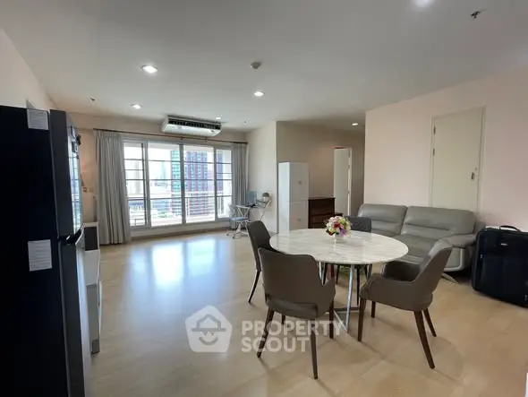 Spacious living room with modern furniture and large windows offering city views.