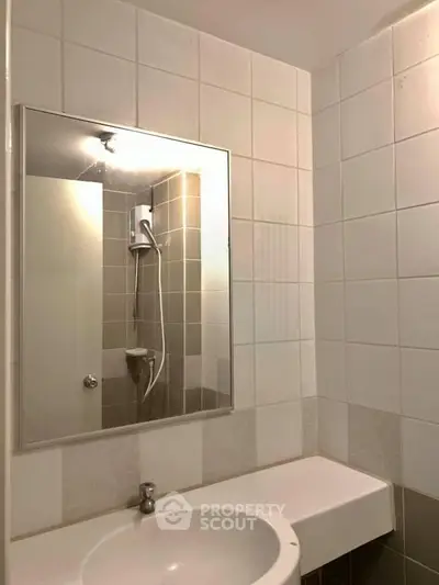 Modern bathroom with sleek white tiles and a stylish mirror above the sink.