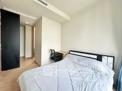 Modern bedroom with sleek design and natural light, featuring a cozy bed and workspace.