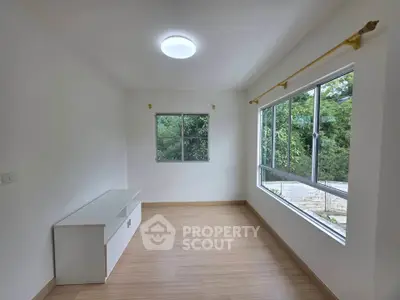 Bright and airy room with large windows and wooden flooring, perfect for a cozy living space.