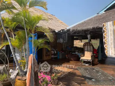 Charming rustic outdoor living space with thatched roof and lush greenery.