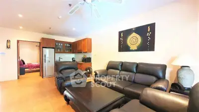 Spacious living room with leather sofas and modern kitchen in open layout apartment.