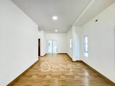 Spacious open-plan living area with wooden flooring and ample natural light.
