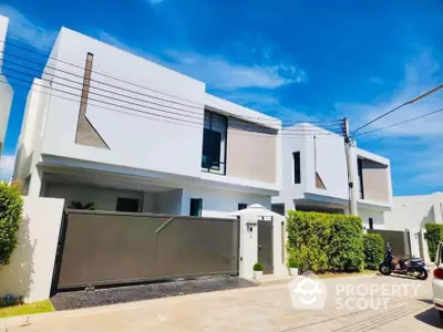 Modern minimalist white house with sleek design and lush greenery in a serene neighborhood.