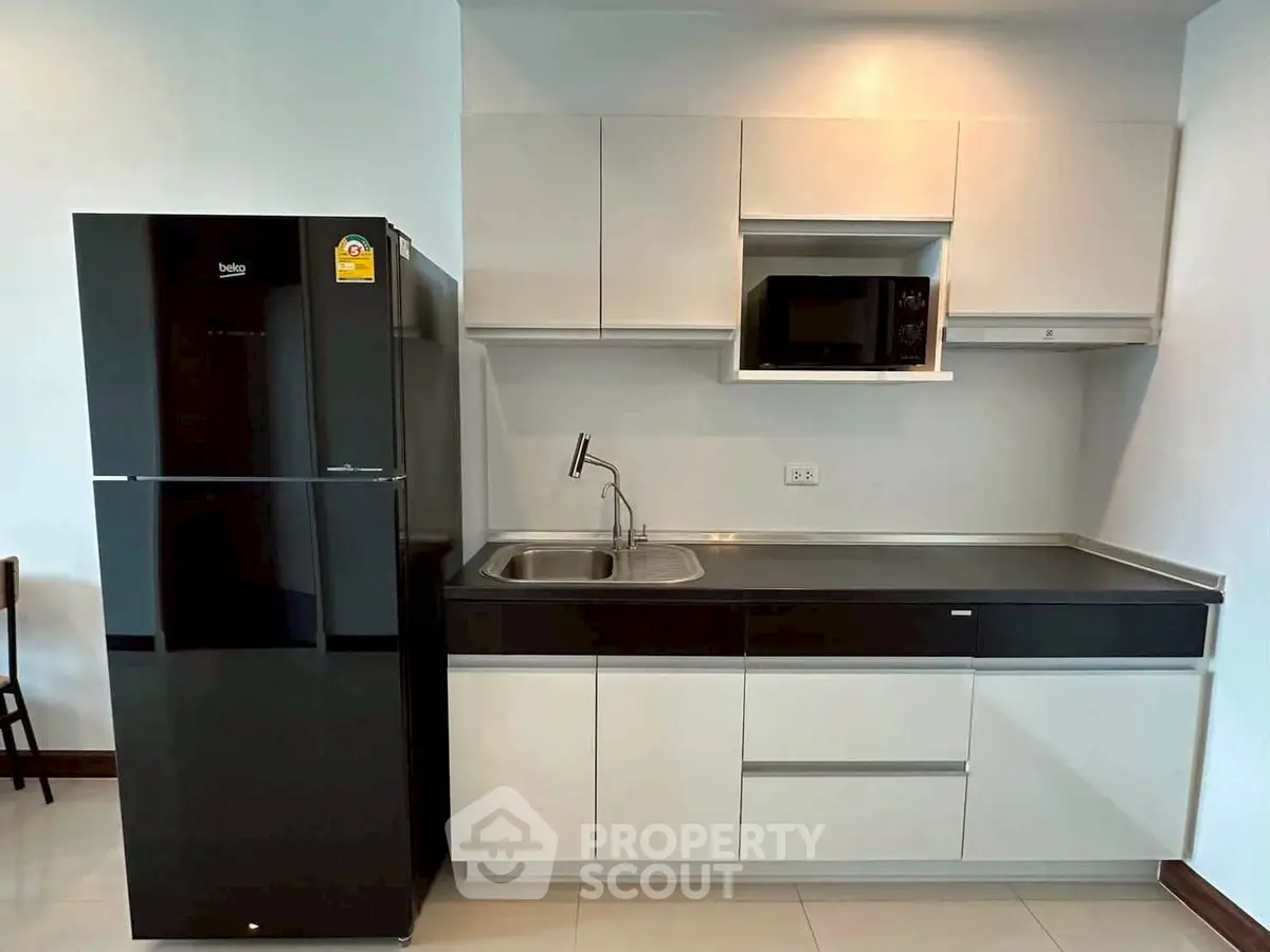Modern kitchen with sleek black fridge and built-in microwave in a compact layout.