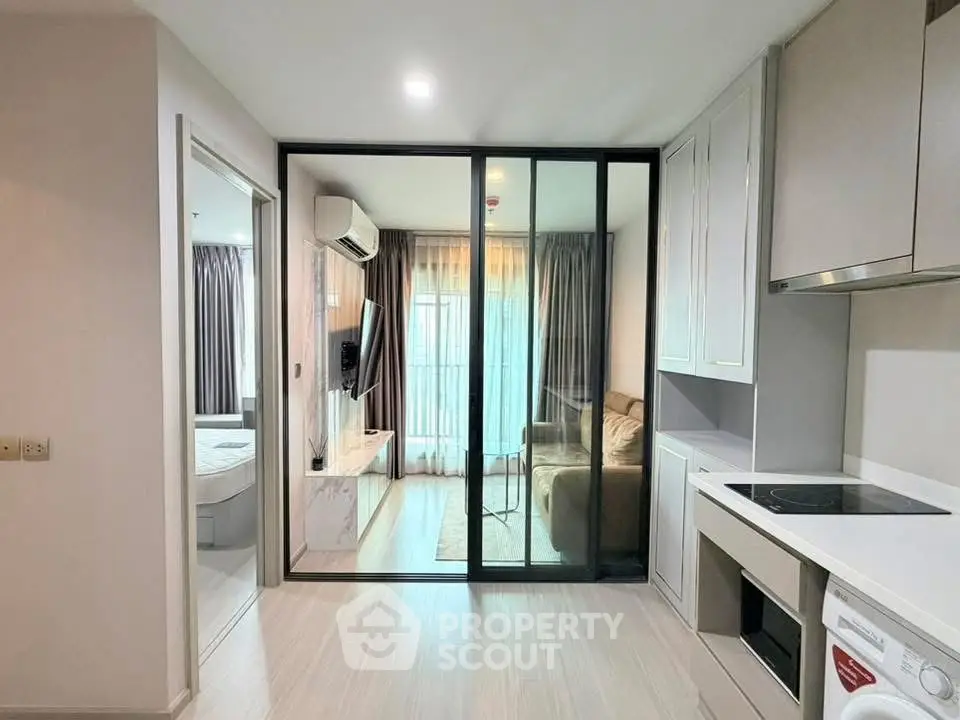 Modern apartment interior with glass partition, cozy living area, and sleek kitchen design.