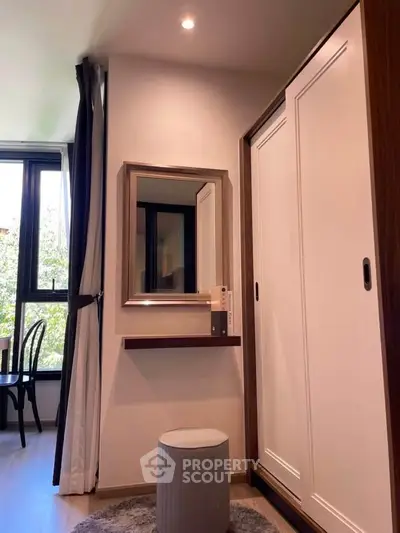 Chic bedroom corner with stylish wardrobe and vanity mirror, offering serene natural light and modern elegance.