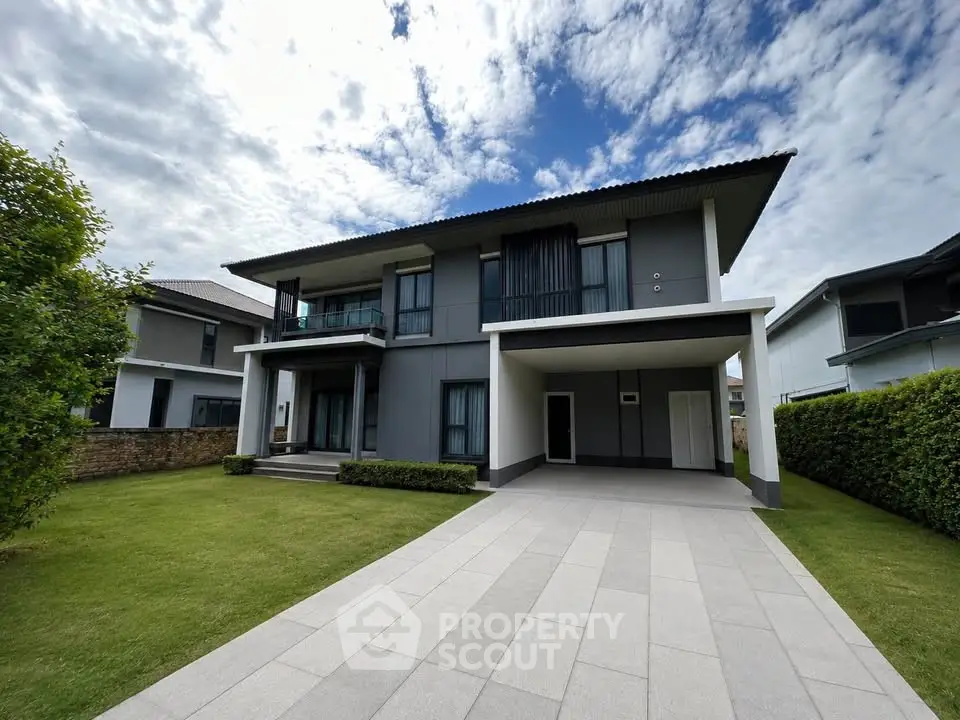 Modern two-story house with spacious driveway and lush green lawn under a partly cloudy sky.