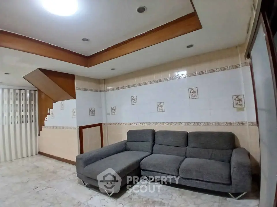 Spacious living room with modern gray sectional sofa and stylish ceiling design.