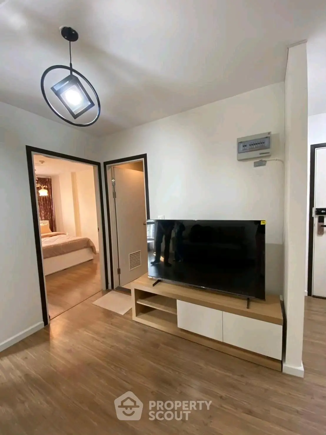 Modern living room with sleek TV stand and view into cozy bedroom