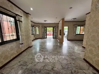 Spacious living room with marble flooring and large windows in a modern home.
