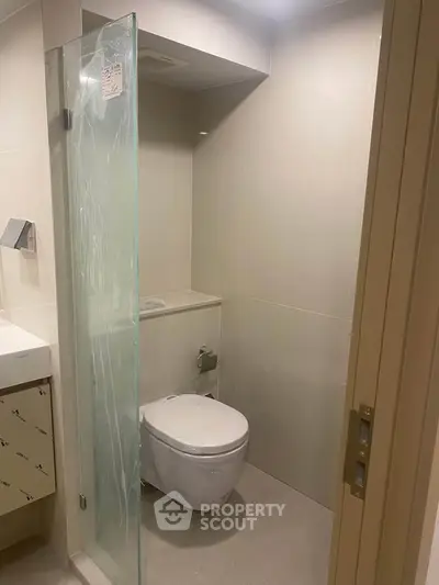 Modern minimalist bathroom with glass shower partition and wall-mounted toilet.