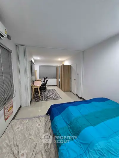 Spacious bedroom with modern decor and study area, featuring a comfortable bed and stylish desk.