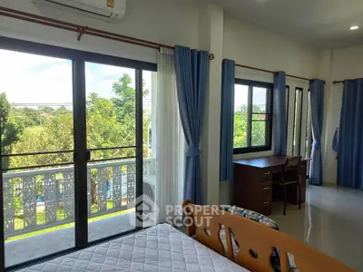 Spacious bedroom with balcony and garden view, featuring large windows and elegant blue curtains.