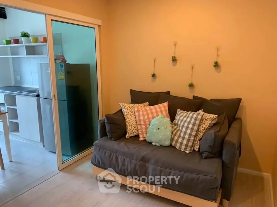 Cozy living room with stylish sofa and view into modern kitchen