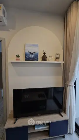 Stylish living room corner with TV, shelf decor, and elegant curtains.