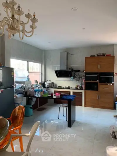 Spacious kitchen with modern appliances and open layout, featuring a stylish chandelier.