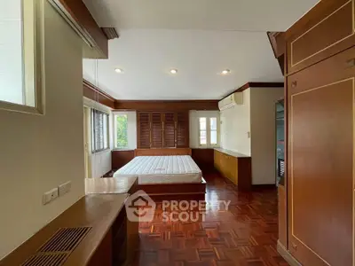 Spacious bedroom with wooden flooring and built-in storage in a modern home.