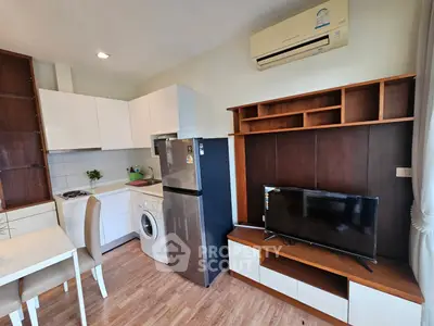 Modern apartment interior with kitchen and living area featuring washing machine and TV unit.