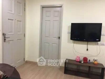 Cozy living room with wall-mounted TV and wooden flooring, perfect for relaxation.