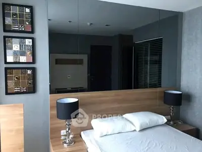 Modern bedroom with stylish decor and mirrored wall for spacious feel