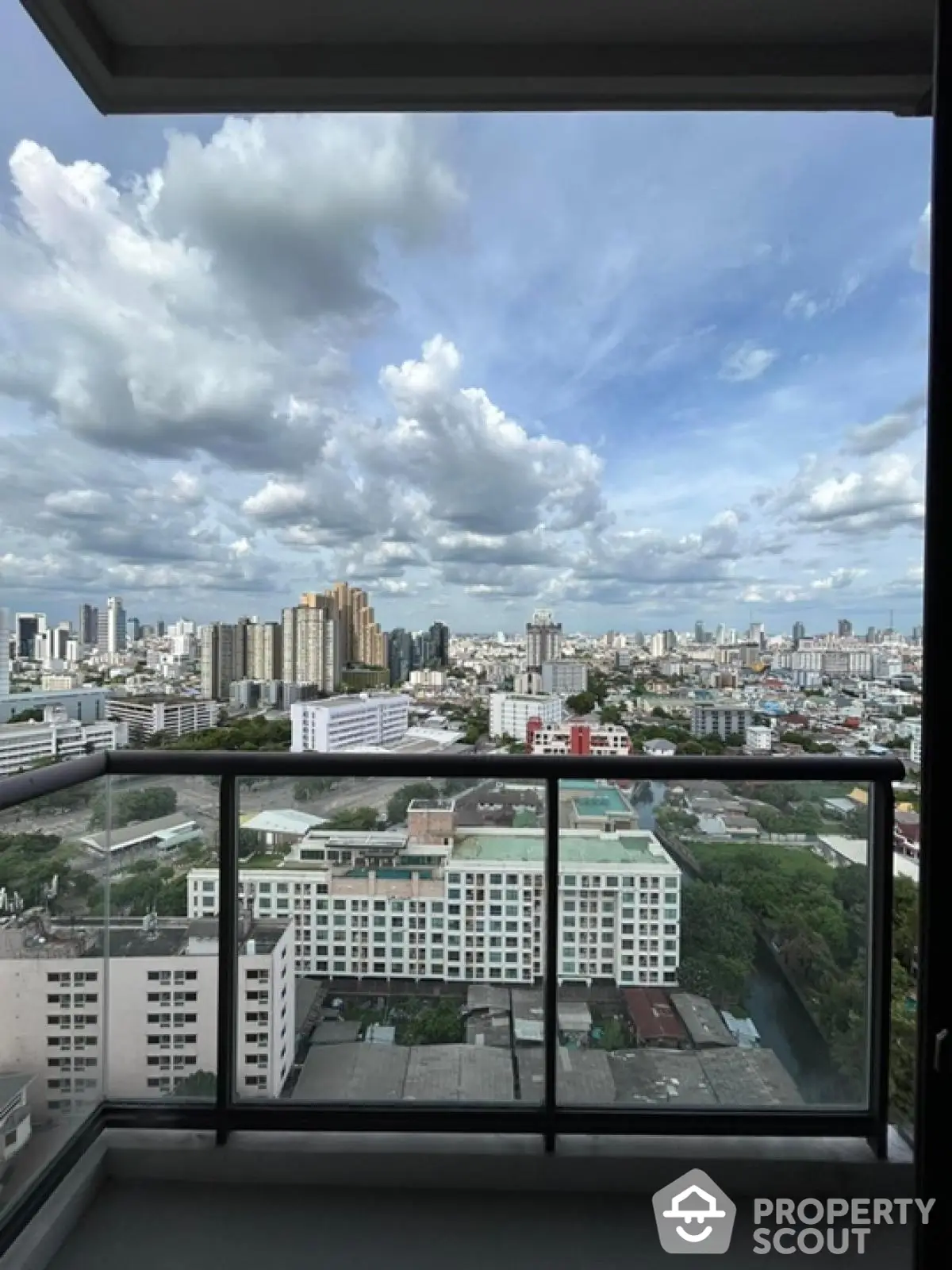 Stunning cityscape view from high-rise balcony with expansive skyline and lush greenery.