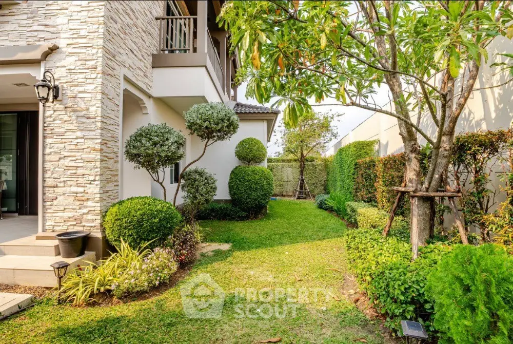 Charming garden view of a modern home with lush greenery and elegant stone facade.