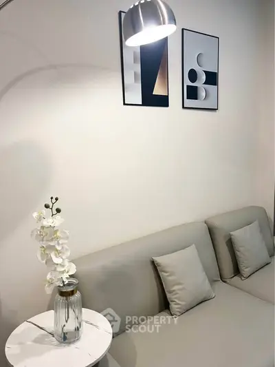 Modern living room with sleek gray sofa, stylish wall art, and elegant lighting for a cozy ambiance.