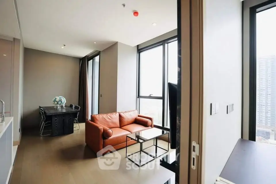 Modern living room with large windows and stylish furniture in a high-rise apartment.
