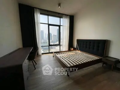 Spacious bedroom with city view and modern furnishings in high-rise apartment.