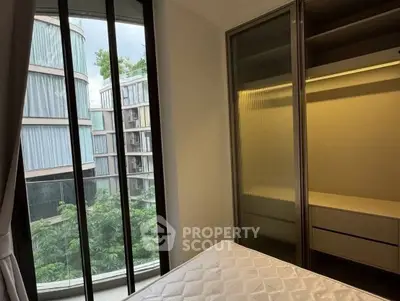 Modern bedroom with large windows and built-in closet overlooking lush greenery.