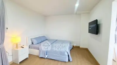 Modern bedroom with minimalist decor and wall-mounted TV in a cozy apartment.