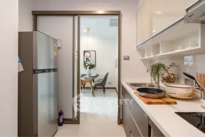 Modern kitchen with sleek appliances and open layout leading to dining area.