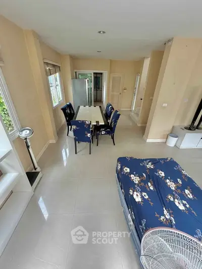 Spacious living room with floral decor and modern dining area in a bright open layout.